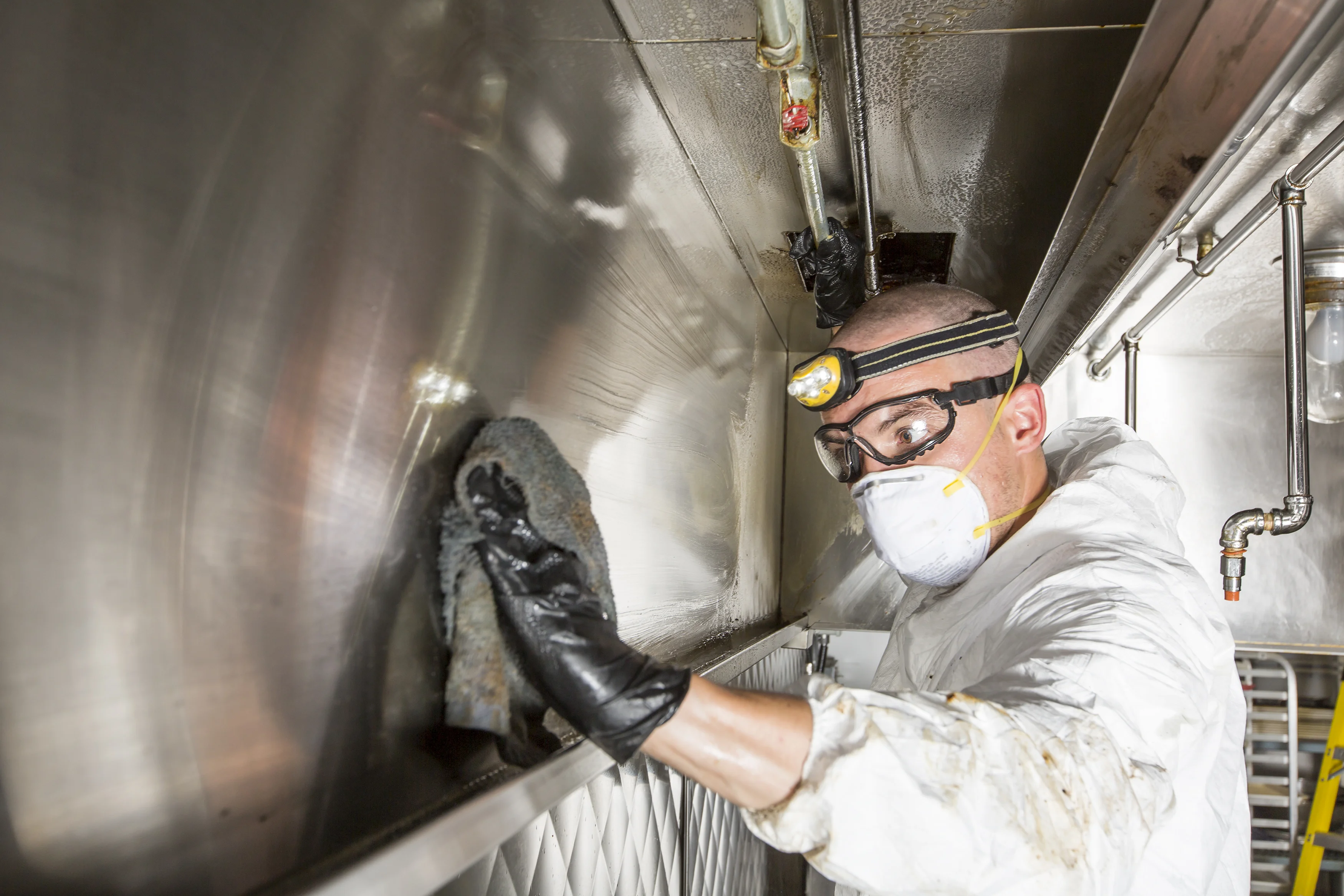 Hood cleaner buffing stainless steel commercial kitchen hood to finish after grease removal
