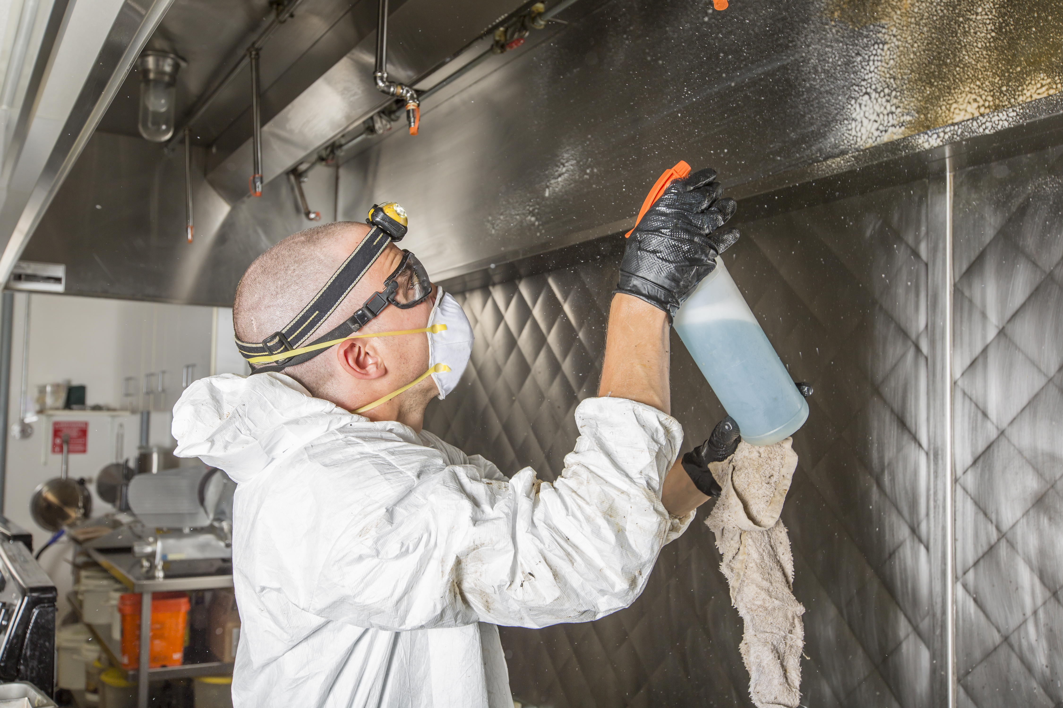 Ontario Hood Cleaning technician hand-cleaning the interior of a commercial kitchen exhaust component during an after-hours service visit